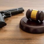 Judge's gavel and handgun on wooden table