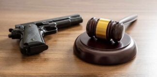 Judge's gavel and handgun on wooden table