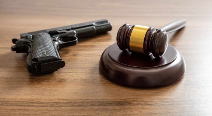 Judge's gavel and handgun on wooden table