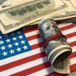 Free Money Frenzy Erupts Nationwide A roll of hundred dollar bills placed on an American flag