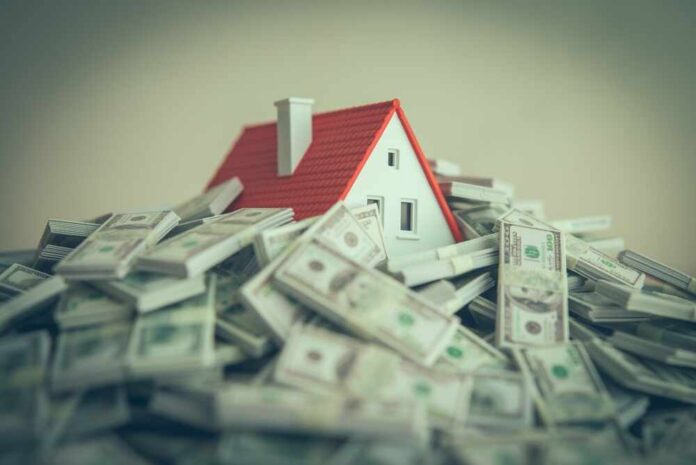A small model house surrounded by stacks of money