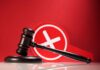 Judge's gavel with a red cross symbol in the background
