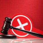 Judge Torches Maxwell: Claims Called Frivolous Judge's gavel with a red cross symbol in the background