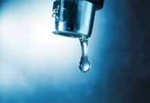 Hand filling pitcher with water from faucet.