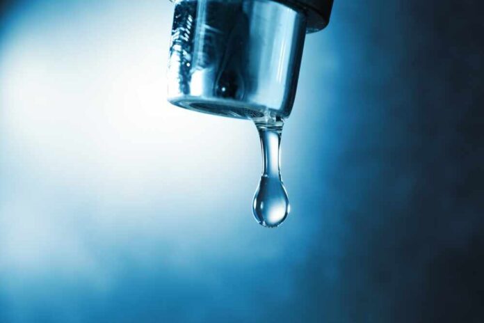 Water,Dripping,Down,From,Faucet,On,Color,Background,,Closeup Hand filling pitcher with water from faucet.