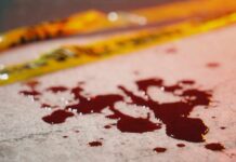Blood droplets on pavement near yellow caution tape