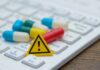 Counterfeit Pills Suspected in Star’s Death? Pills and warning sign on a computer keyboard