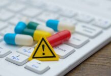 Counterfeit Pills Suspected in Star’s Death? Pills and warning sign on a computer keyboard