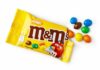 Candy Shake-Up: What’s Missing From M&M’s? M&M's candy bags with scattered colorful candies on a white table
