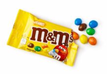 M&M's candy bags with scattered colorful candies on a white table