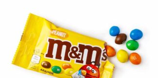 M&M's candy bags with scattered colorful candies on a white table