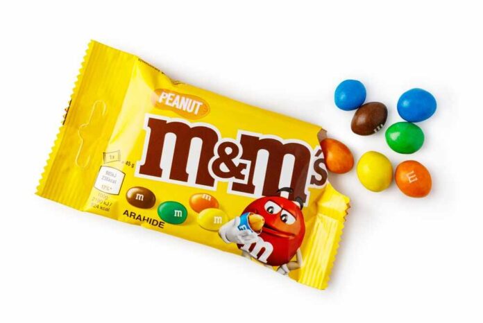 M&M's candy bags with scattered colorful candies on a white table