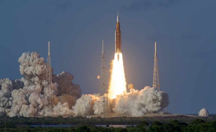Artemis,Ii,Launch:,Nasa's,Space,Launch,System,(sls),Rocket,And Rocket launching from a coastal pad at dawn with bright exhaust plume