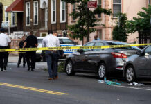 Deadly Drive-By Mass Shooting Shocks Community Police and crime scene tape on city street.