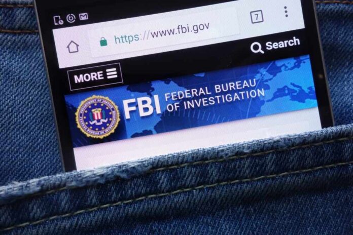 shutterstock_1099317668-1 Mobile phone displaying the FBI website in a denim pocket