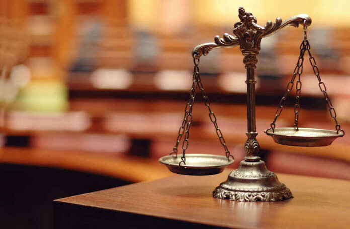 shutterstock_140867215 Scales of justice in an empty courtroom.