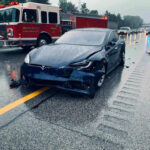 Car crash with a Tesla on a rainy highway.