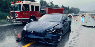 Car crash with a Tesla on a rainy highway.