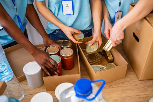 Homeless,Care.,Charity,Team,Of,Volunteers,Putting,Food,And,Drinks Volunteers organizing canned goods and jars for a food donation