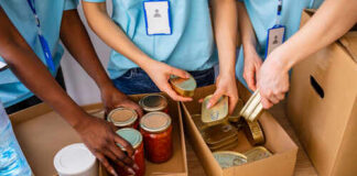 Volunteers organizing canned goods and jars for a food donation