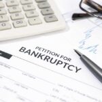 Bankruptcy petition form with pen, calculator, and eyeglasses