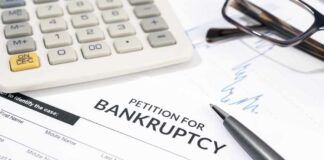 Bankruptcy petition form with pen, calculator, and eyeglasses