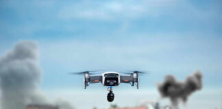 Drone flying over urban area with smoke plumes.