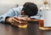 Drinking Plunge Stuns America Person asleep at table holding drink glass