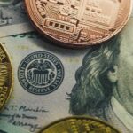 Close-up of a Bitcoin and other coins on a US dollar bill