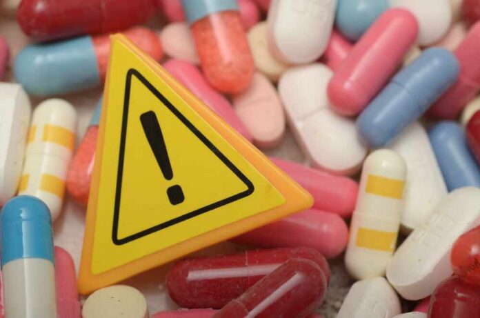 Caution:,Health,Risks,Ahead,-,Warning,Sign,And,Pill,Capsule Warning sign among assorted pills and capsules