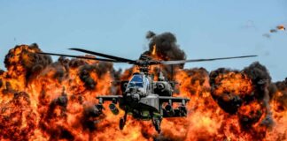 Attack helicopter flying in front of a massive explosion