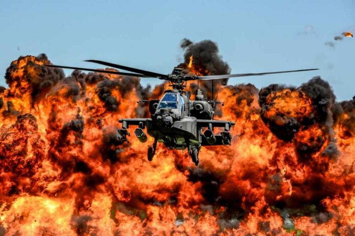 U.s.,Army,Ah-64d,Apache,Attack,Helicopter,,Assigned,To,The,1-151st Attack helicopter flying in front of a massive explosion