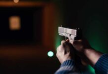Hands aiming a pistol at an indoor shooting range