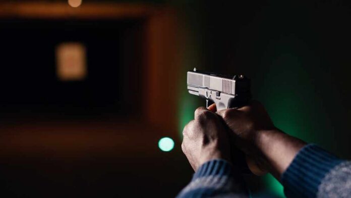 Man,Holding,Pistol,Enjoying,Recreational,Indoor,Shooting,Experience,In,Firing Hands aiming a pistol at an indoor shooting range
