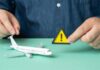 U.S. Issues Travel Alert – City on Edge A person holding a warning sign next to a model airplane