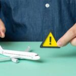 U.S. Issues Travel Alert – City on Edge A person holding a warning sign next to a model airplane