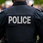 Back view of a police officer wearing a uniform with 'POLICE' displayed