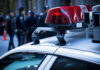 3 Dead: Dawn Shootout Shocks Neighborhood Police car roof with lights, officers in background.