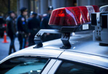 3 Dead: Dawn Shootout Shocks Neighborhood Police car roof with lights, officers in background.