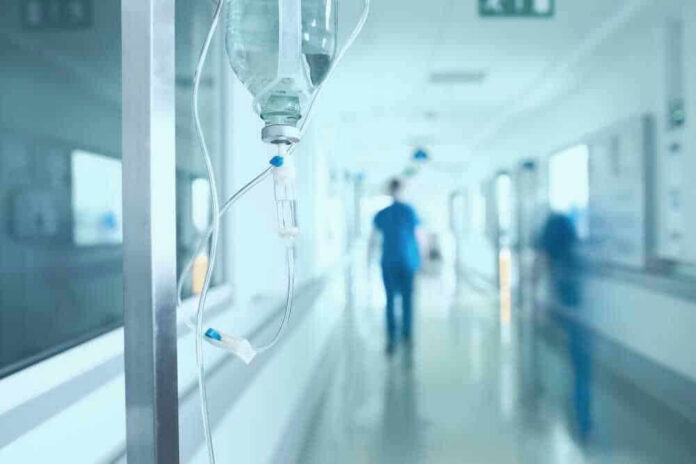 shutterstock_528854752-1 Hospital corridor with IV drip and healthcare worker.