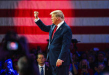 Trump’s Latest Gambit Shocks Allies Donald Trump raises a fist on stage before a large U.S. flag