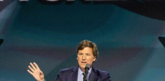 Tucker Carlson speaking at a podium with a microphone
