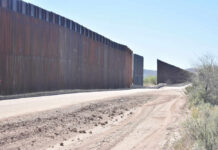 DOJ’s Emergency Play: Border Build Back On? Dirt road beside tall metal border wall