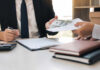 Jobs Shock Rocks Markets Two individuals engaged in a business transaction involving money and documents