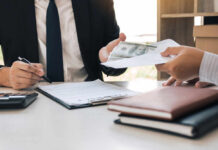Jobs Shock Rocks Markets Two individuals engaged in a business transaction involving money and documents