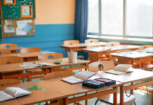 $930M Bombshell Hits Classrooms Classroom with wooden desks and open notebooks in natural light