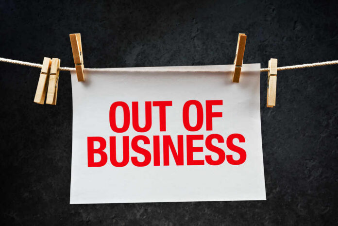 Out,Of,Business,Note,Printed,On,Paper,Hanging,On,Rope paper sign with red lettering clipped to a clothesline