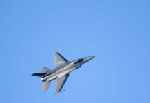 A commercial airplane flying above two military jets in a clear blue sky