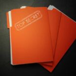 Secret Files: Saudi Link Bombshell? A stack of orange folders labeled 'TOP SECRET' on a dark surface