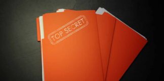A stack of orange folders labeled 'TOP SECRET' on a dark surface